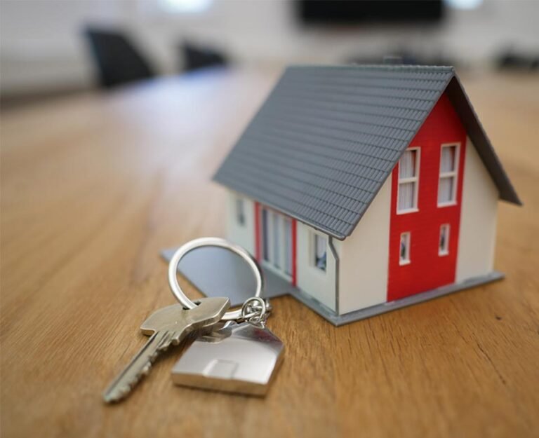 Casa miniatura de madera acompañando un llavero sobre un escritorio